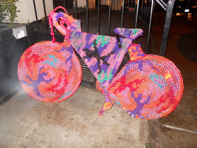 A bicycle covered in crocheted yarn in various colours.