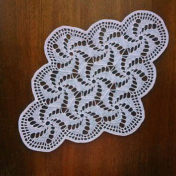 A white doily with a spiral pattern on a wooden surface.