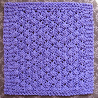 A purple knitted dishcloth featuring a diamond lace pattern.